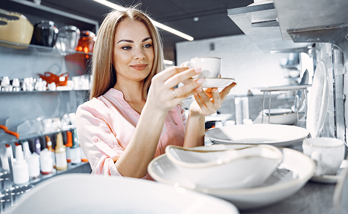 Woman in a pink blouse buys dishes in the store